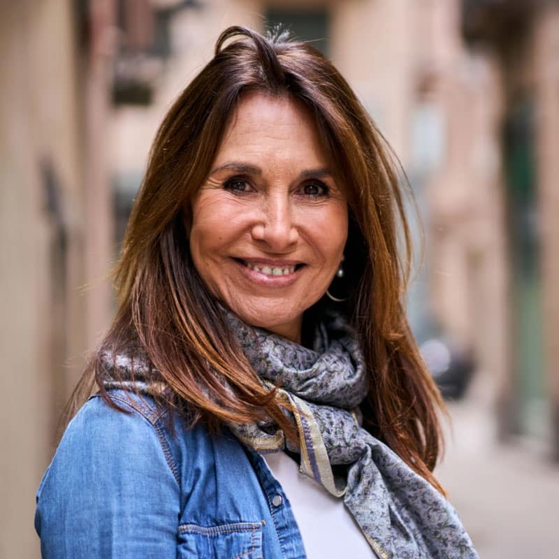 Donna felice con sciarpa e giacca in un ambiente urbano di erbe.